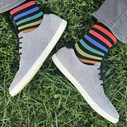 Gray sneakers with colorful striped socks on grass