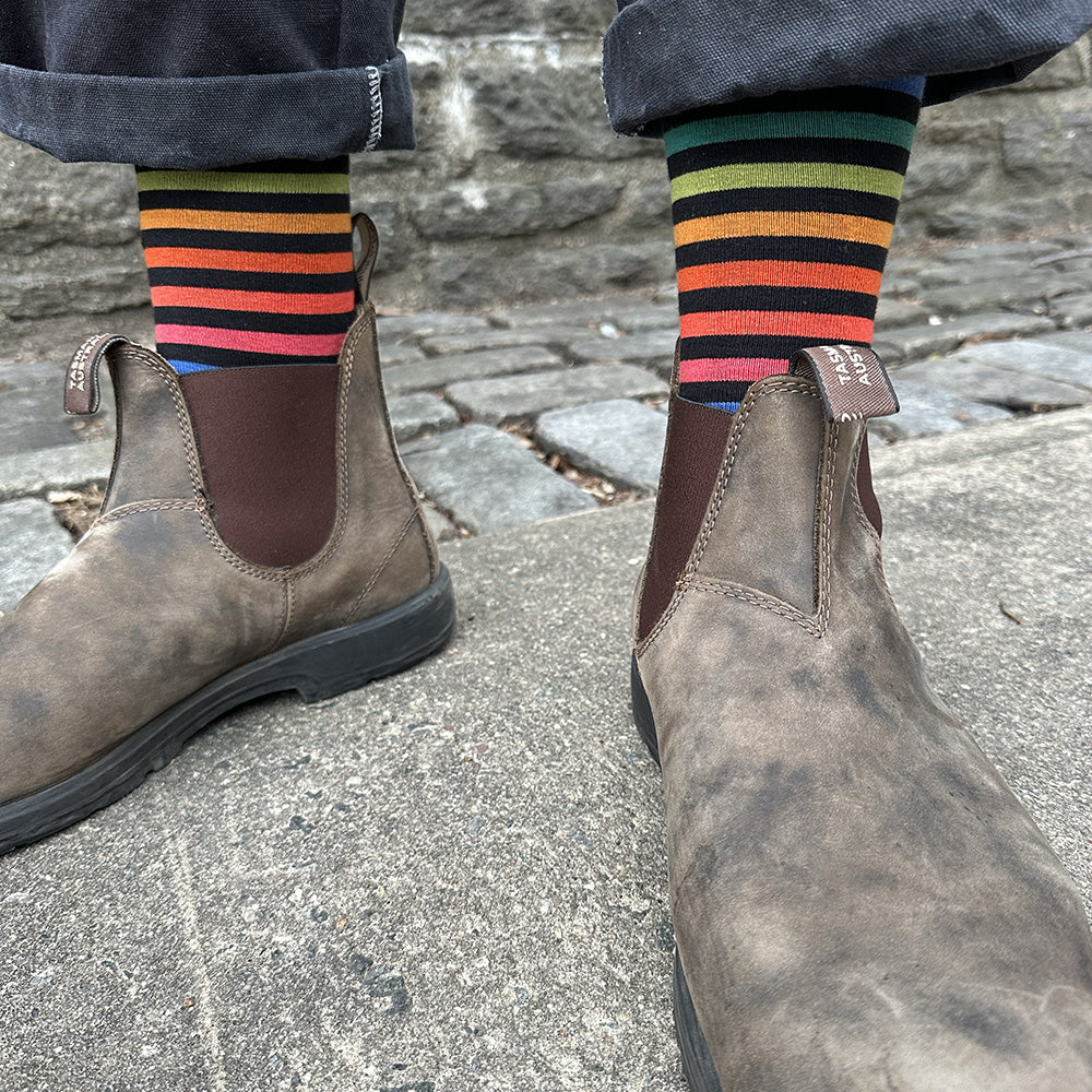 Brown leather boots with striped socks on a stone pavement