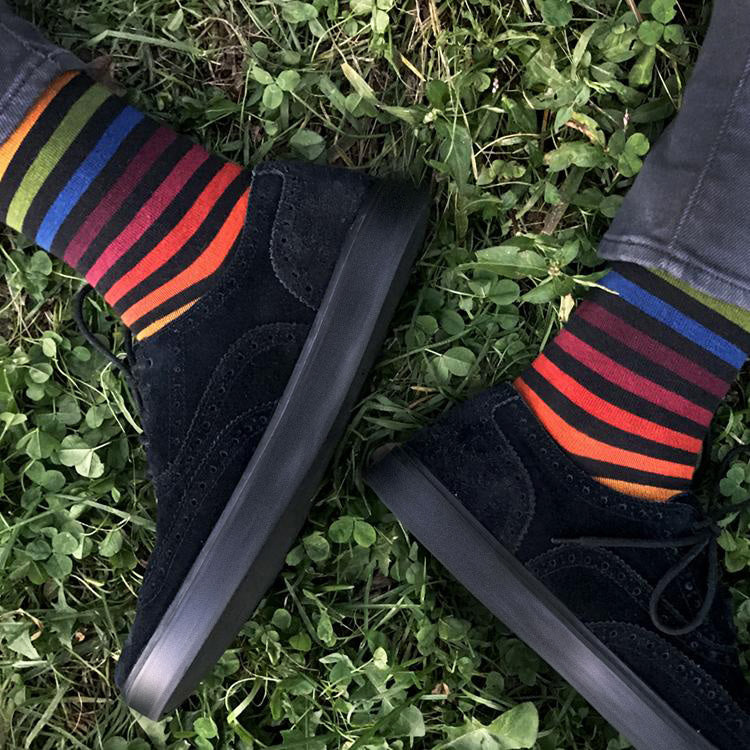 Black shoes with colorful striped socks on grass