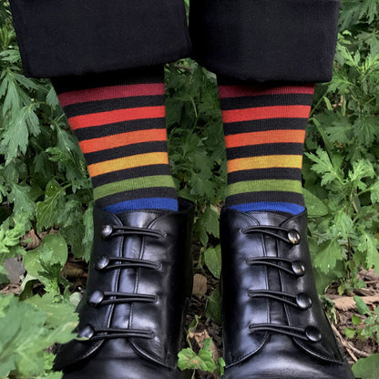 Colorful striped socks worn with black leather shoes against a green leafy background