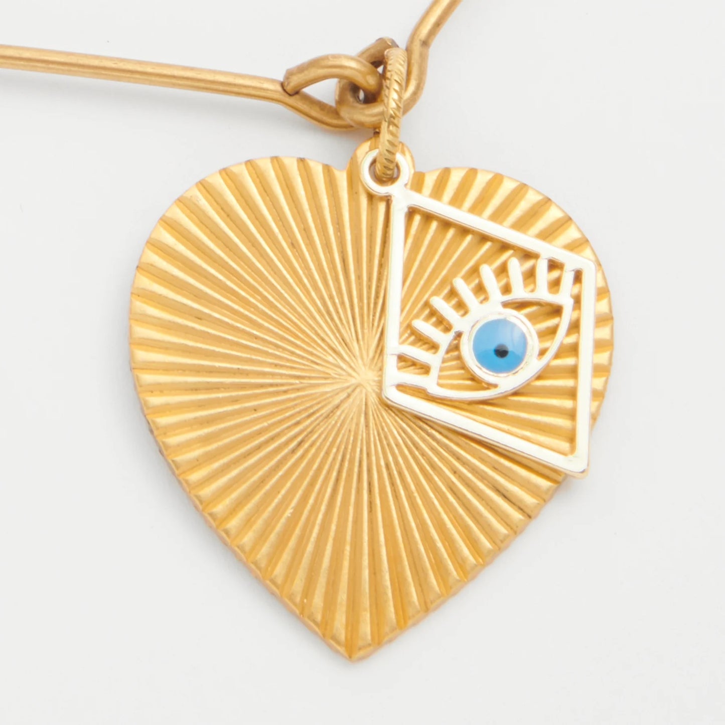 Gold heart-shaped pendant with eye design on a white background