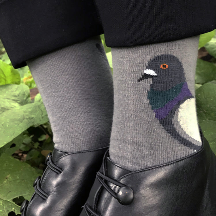 Gray socks with a pigeon design worn by a person in a natural setting.