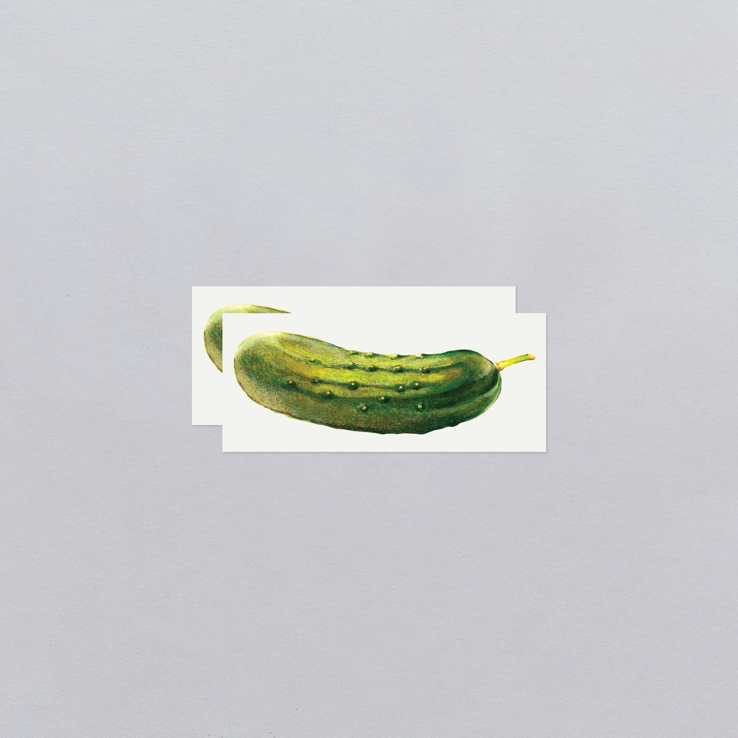Two green pickle temporary tattoos on a white background