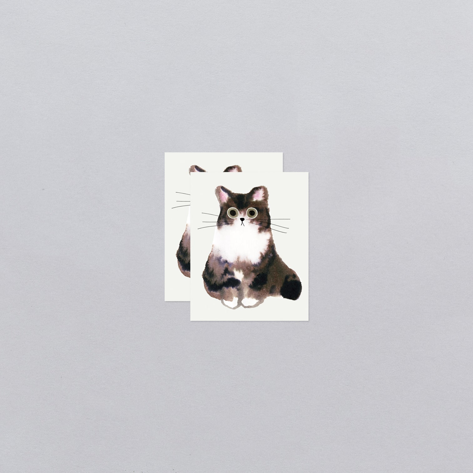 Two temporary tattoos with a cat illustration on a gray background