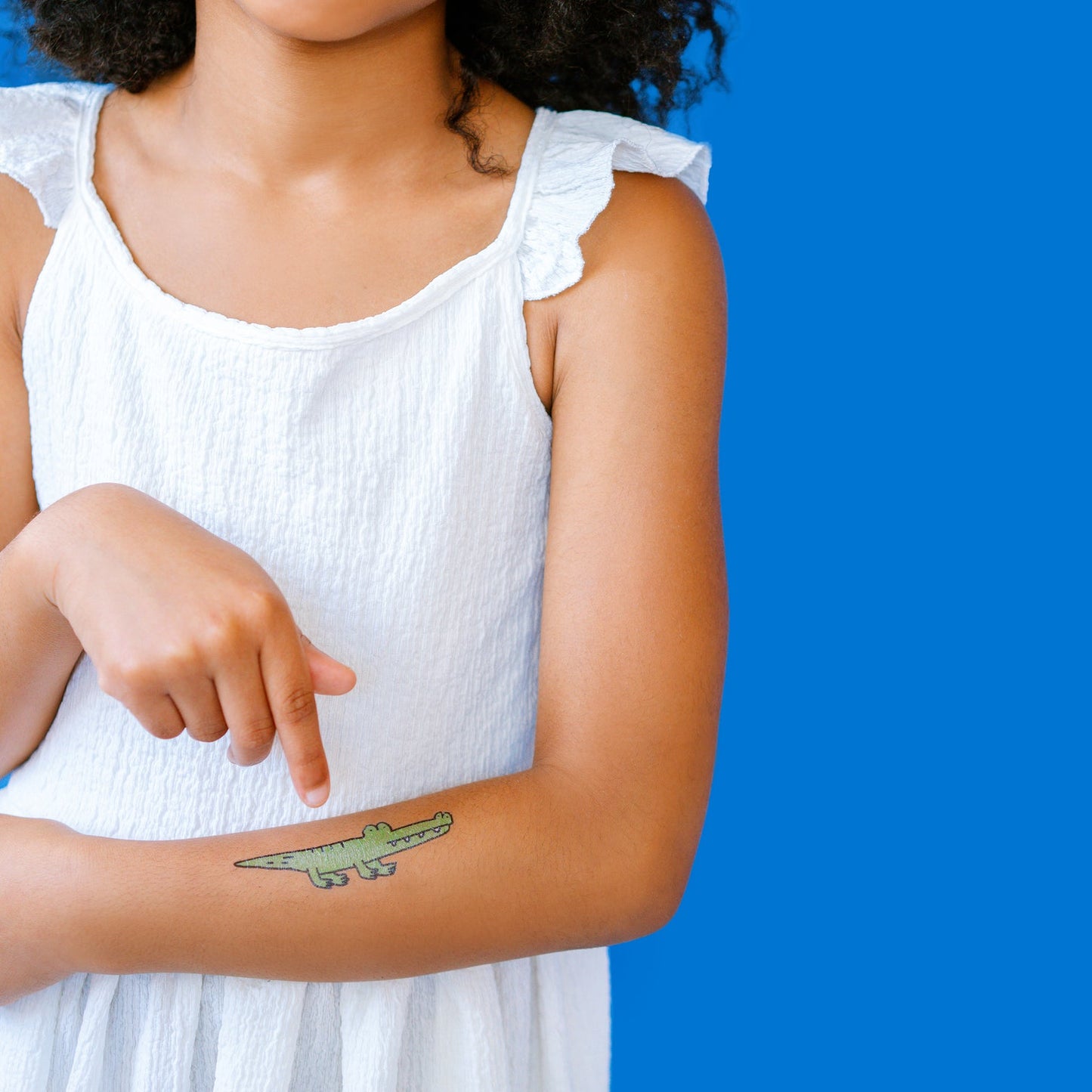 Person wearing a temporary green alligator tattoo on their arm against a blue background