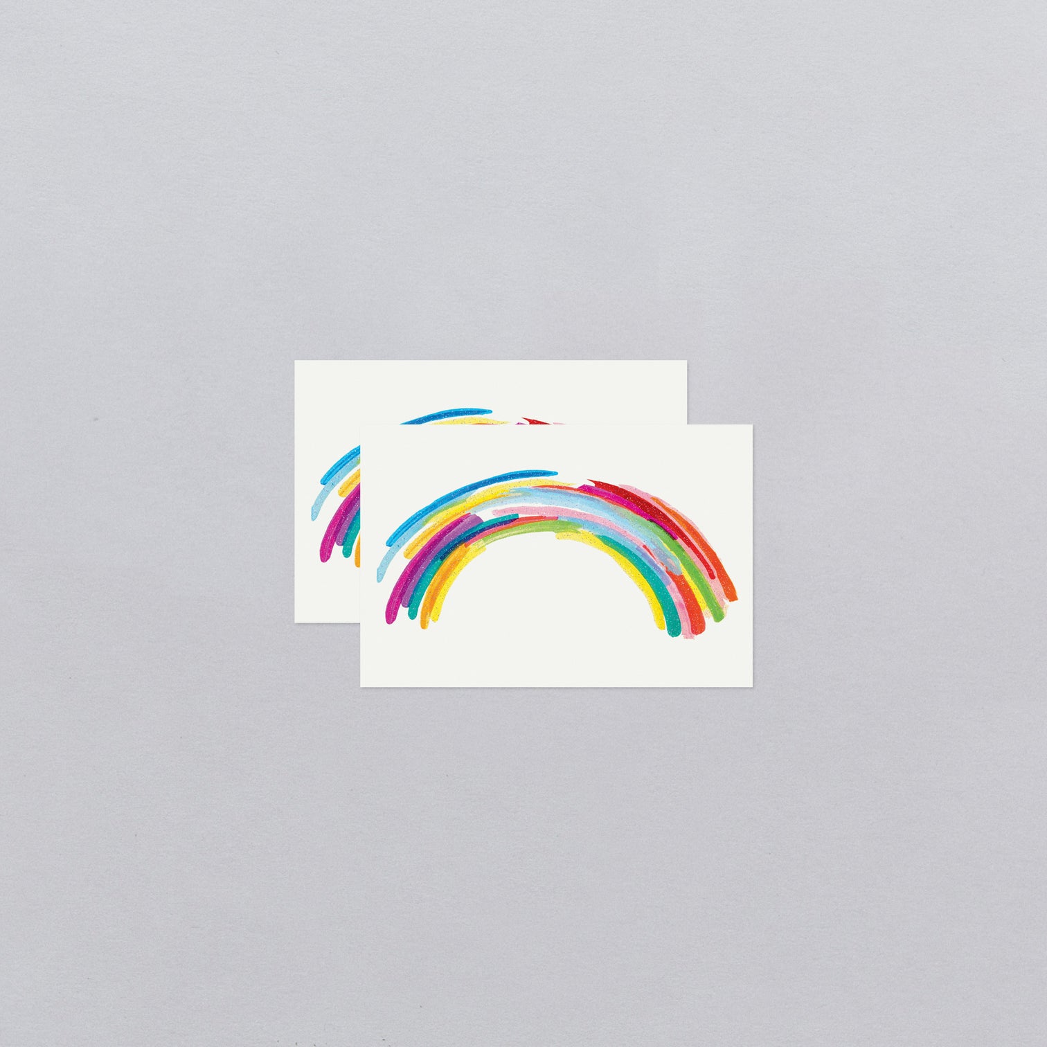 Two rainbow-shaped temporary tattoos on a gray background