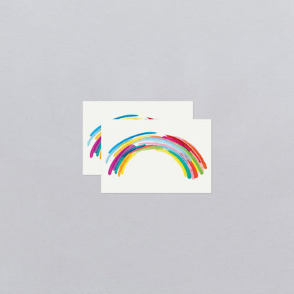 Two rainbow-shaped temporary tattoos on a gray background