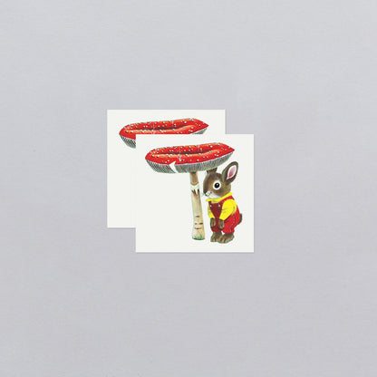 Two temporary tattoos with a rabbit and toadstool design on a gray background